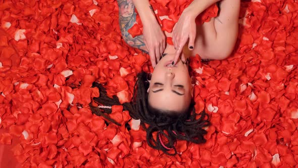 Portrait of Beautiful Girl lies in petals red roses