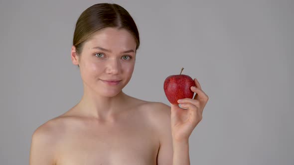 Young beautiful girl holding apple smiling and enjoying natural skin care alt