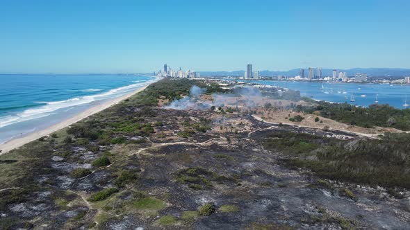 Popular holiday nature reserve destroyed by fire close to a city beach and boating harbour. Panning alt
