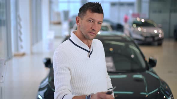 Confident Successful Man Looking Back at Luxurious New Automobile Showing Car Key Looking at Camera alt