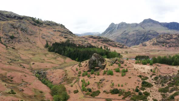 Aerial View Over Hills Towards Mountains