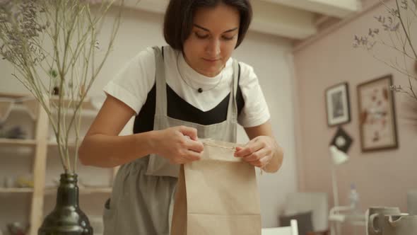 Craftswoman Wrapping Clay Item Into Paper Bag