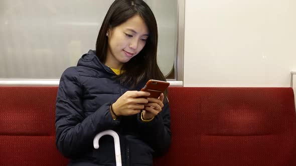 Woman using cellphone inside train compartment alt