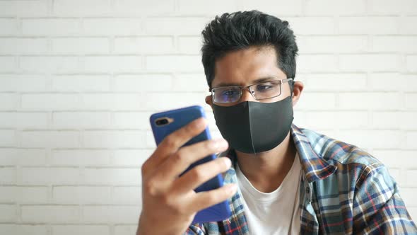 Sick Man in Surgical Face Mask Using Smart Phone Selective Focus alt