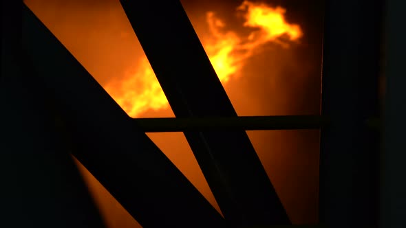 Flames Are Burning Behind the Metal Pillars of an Industrial Building