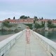 A Long Stone Bridge with Pretty Woman Walking From the Island Washed By the Sea