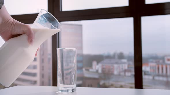 Woman Pours Milk From a Jug Into a Glass Indoors Close Up Cinematic Shot