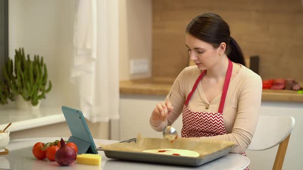 Female Chef Preparing a Pizza and Watching Recipes Online on Platform for Watching Videos on Your
