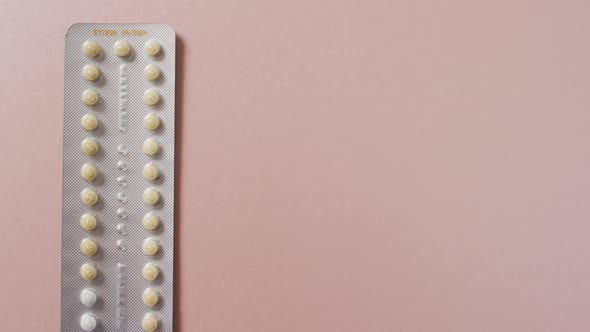 Video of close up of yellow tablets on pink background alt