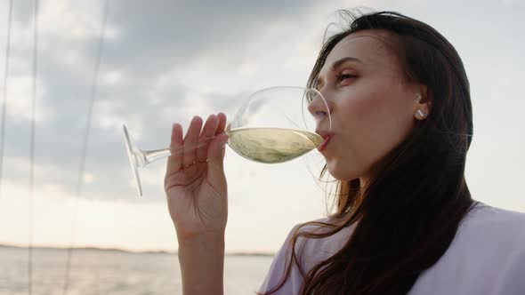 Young Woman in a Good Mood Who Drinks Wine During a Boat Trip on a Yacht alt