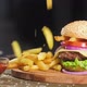 French fries fall on a hamburger lying on a wooden tray. nearby sauce in Cup - VideoHive Item for Sale