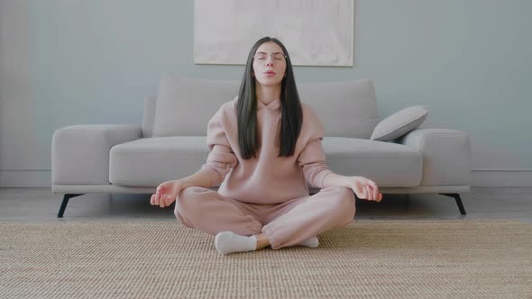 Young millennial girl meditating sitting on floor in lotus position.