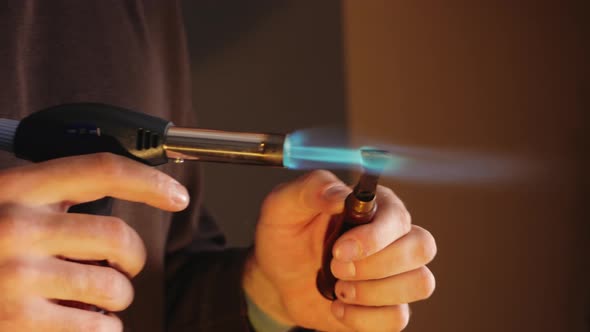 Man Heats Tool with Gas Burner Indoor Closeup Authentic