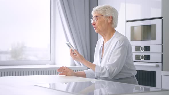 Aged mother with short grey hair waves hand and talks with adult children alt