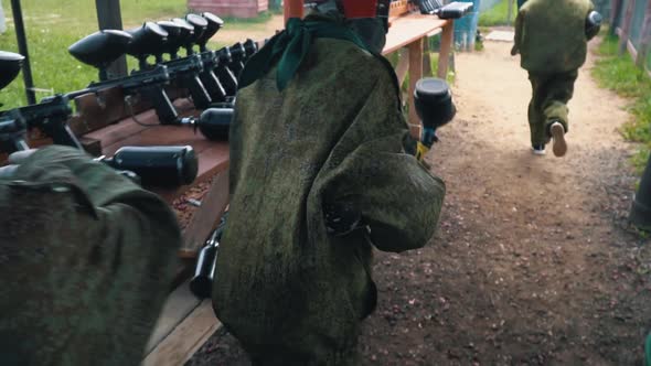 Paintball Players in Camouflage Uniforms Take Guns and Run alt
