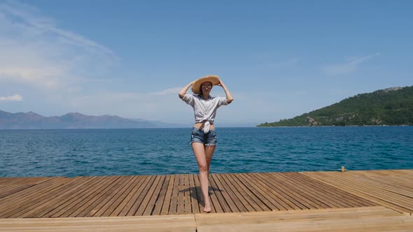 Young Sexy Girl in a Hat and Shorts Walking on the Pier alt