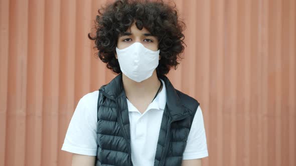 Slow Motion Portrait of Middle Eastern Teenager Standing Outdoors Wearing Medical Face Mask During alt
