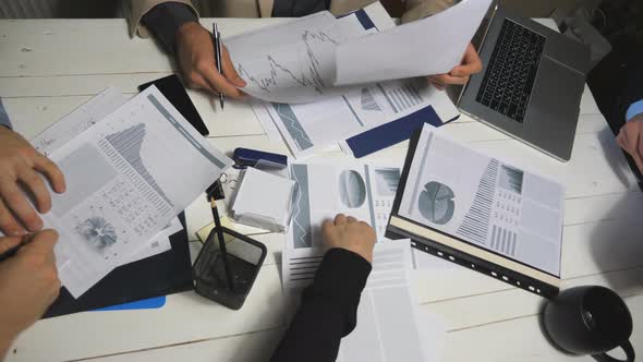 Top View Male and Female Hands of Colleagues Analyzing Financial Reports in Office alt