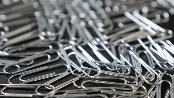 Metal or steel wire clips for documents  in office on wooden table close-up slow tilt 4K 2160p 30fps alt