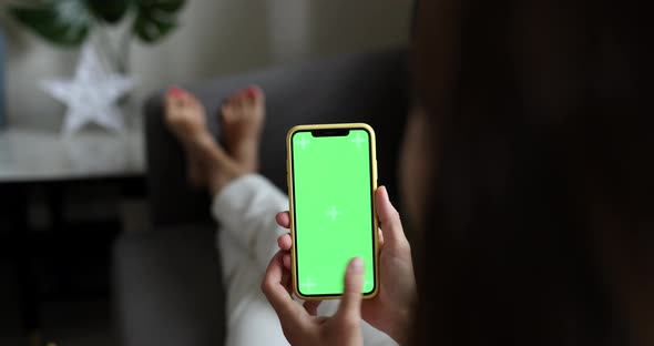 Young woman using mobile phone with chroma key at home when resting on sofa at home alt