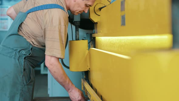Worker Cuts Metal Sheets on Mechanical Guillotine Machine in Production Hall