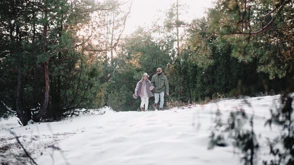 Cute Couple Happily Running in the Woods Holding Hands in Winter at the Sunset