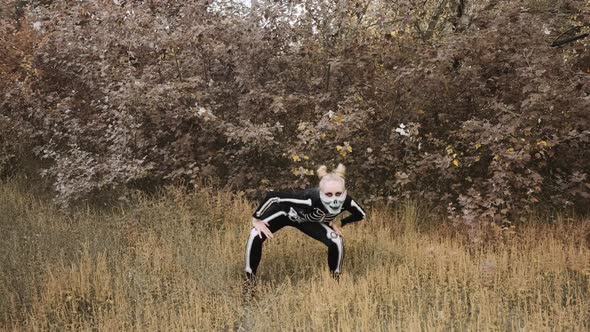 A girl with a scary make-up in a skeleton costume, a mask with rhinestones in a gloomy autumn forest alt