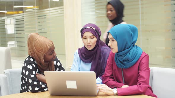 Muslim Asian and African Women in Hijabs Sit in Cafes and Make Online Purchases Using a Laptop