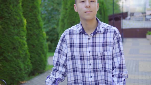 Young Asian Man with Broken Leg on Crutches Walking in Park alt