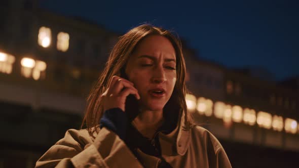 Young woman in the city at night picks up her phone and starts talking alt