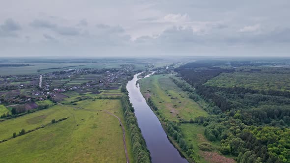 Top View of the River Surrounded By Trees and Meadows alt