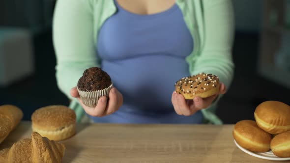 Woman Holding Muffin and Donut, Lots of Pastry on Table, Overeating Sweets alt