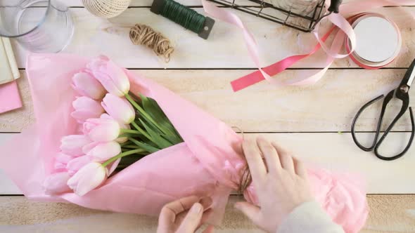Step by step. Florist wrapping pink tulips in bouquet alt