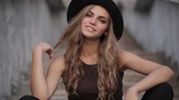 Attractive white Caucasian girl in black hat smiling on the street alt