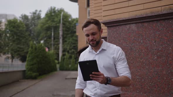 Young Worker Talks Outdoor on His Black Tablet alt