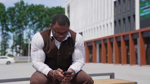 Portrait of handsome black young man texting message on mobile phone alt