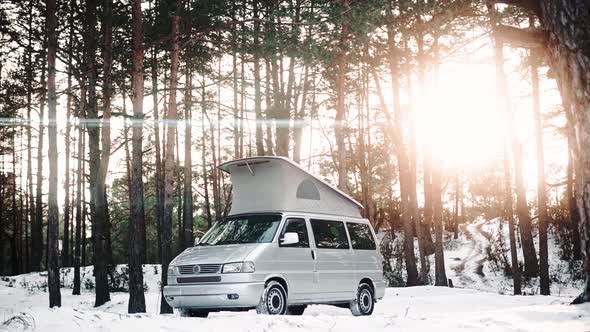 Modern Camping Van with Pop Up Roof Parked in the Woods on a Sunny Winter Day alt