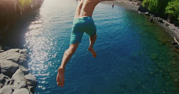 POV shot of young adventurous man jumping into beautiful ocean pool alt