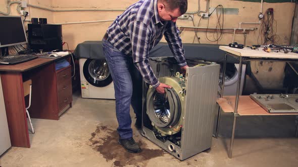 A Man Removes a Plastic Drum From a Metal Case alt