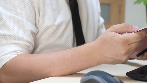 Man Holds Credit Card and Using Smartphone in Office