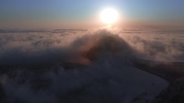 Sun Raising Above Horizon in Clear Blue Sky with Golden Clouds Covering Shore alt