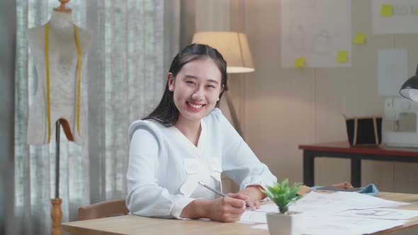 Asian Woman Designer With Layout Bond Smile To Camera While Working With Laptop At The Office alt