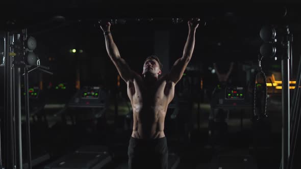 Wellness Athletic Man Performs Pullups on the Horizontal Bar Strength Training in the Gym at Night alt