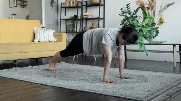 Strong fit young woman is practising plank position at home developing stamina and strength alt