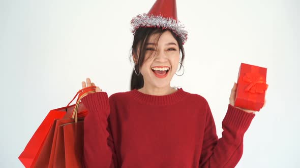 slow-motion of cheerful woman holding Christmas gift box and shopping bag