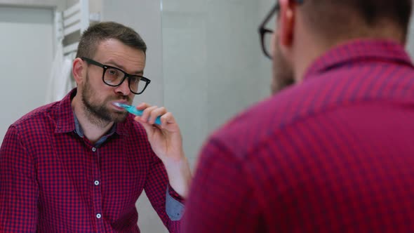 Bearded Man Brushing His Teeth in a Bathroom in the Morning alt