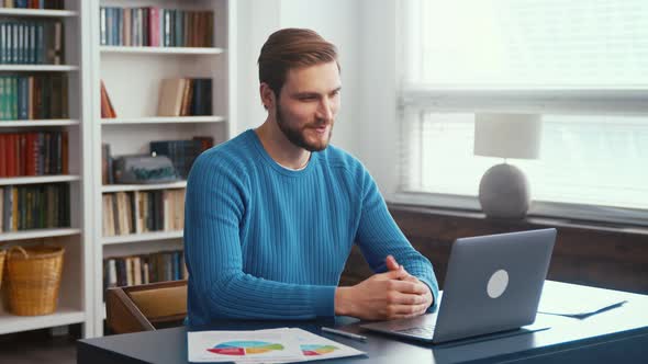 Young male in headphones talk on video call on computer alt