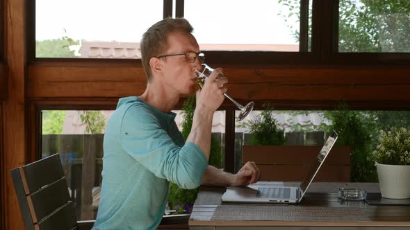 Man Drinking Wine And Chatting In Messenger On Laptop