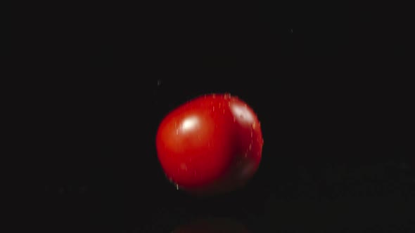 Tomato Falls In Water In Dark And Splashes Scatter In Different Directions