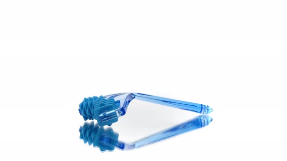 Blue Plastic Facial Massager Reflected in Glass 360 Rotating Isolated on White alt